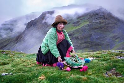 Une femme quechuadans les Andes effectuant un rituel avec des feuilles de coca pour prévenir le mal de l’altitude - Pérou