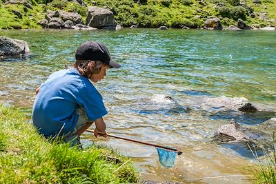 Petit garçon en train de pêcher avec une épuisette au bord d'une riviere - France