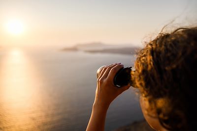 Une personne regarde le coucher de soleil à travers des jumelles - Grèce
