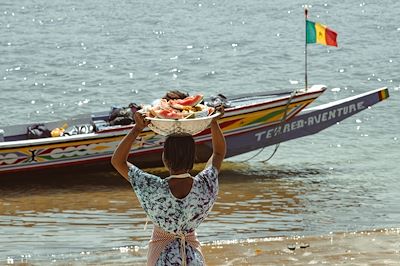 Personne portant une panière de fruits face à la mer au Sénégal