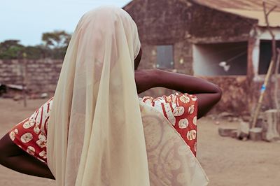 Femme de dos devant une maison dans un village du Sine Saloum au Sénégal