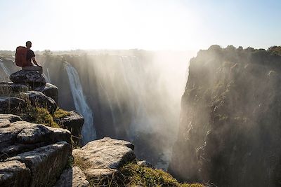Randonneur devant les chutes Victoria au Zimbabwe